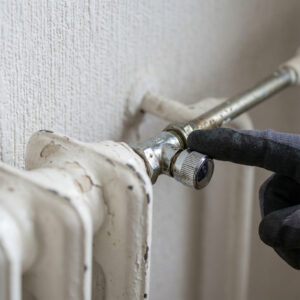 Der Finger eines Experten zeigt präzise auf das Ventil, das den Heizkörper von den zentralen Versorgungsrohren trennt.